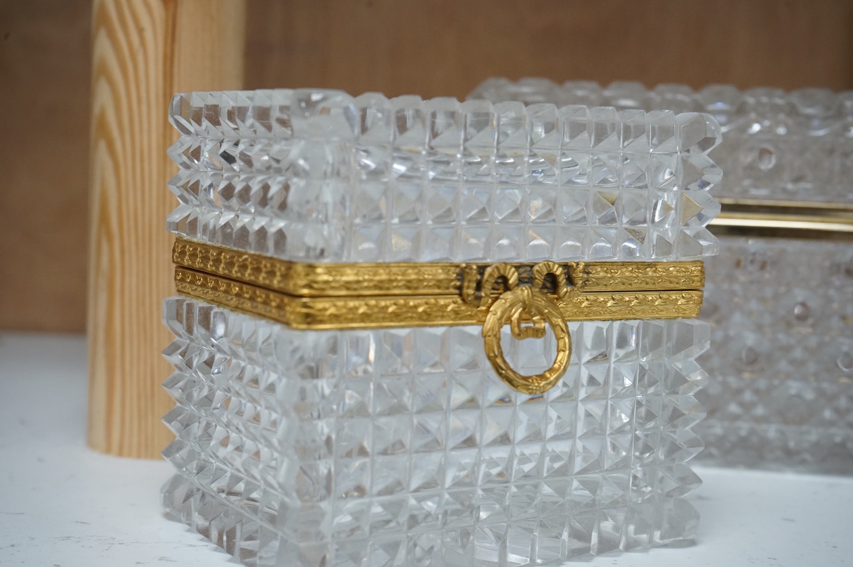 A deeply cut rectangular glass casket, a similar smaller casket and a cylindrical container, all with gilt metal mounts, largest 18cm wide x 10.5cm high.